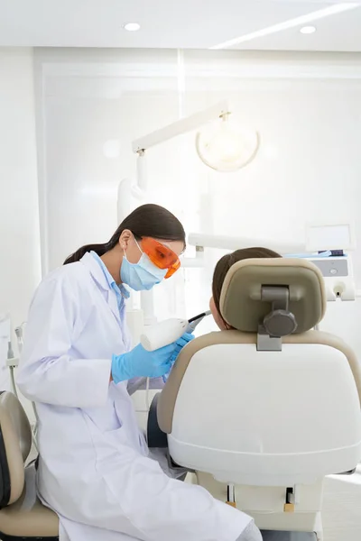 Female dentist wearing goggles when drilling teeth