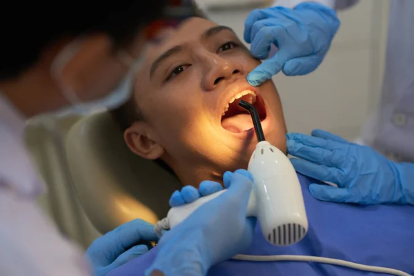 Dentist using curing UV lamp on teeth of patient