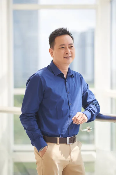 Nachdenklich Lächelnder Asiatischer Geschäftsmann Der Durch Das Bürofenster Blickt — Stockfoto