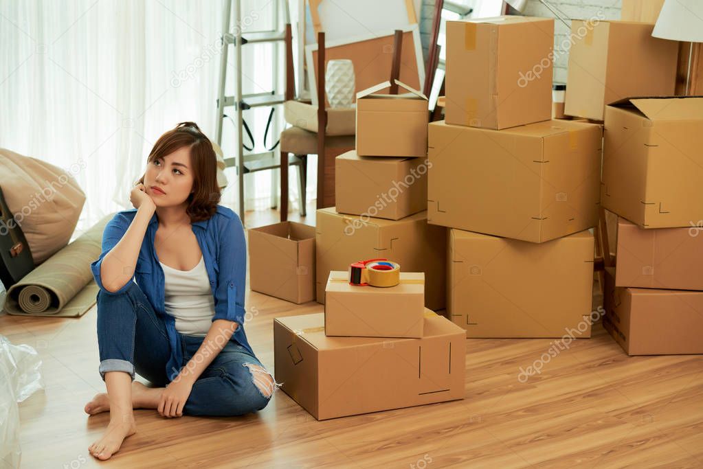 Young Asian woman tired of packing sitting on the floor