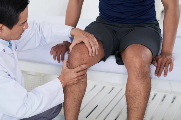 医師男性スポーツマンの膝関節をチェック — ストック写真