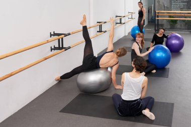 Kadın eğitmen üzerinde egzersiz gösterilen genç kadınların baloya uygun