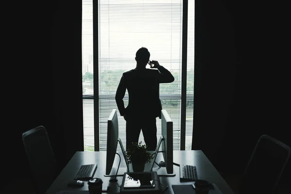 Bakifrån Affärsmannen Stående Mot Office Fönster Och Telefon — Stockfoto