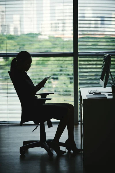 彼女のオフィスでのデジタル タブレット上で何かを読んで女性起業家のシルエット — ストック写真