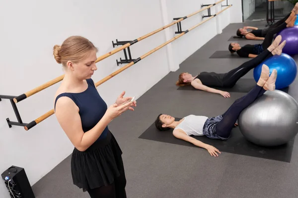 Instructor Verificando Tiempo Teléfono Inteligente Cuando Las Mujeres Jóvenes Realizan — Foto de Stock