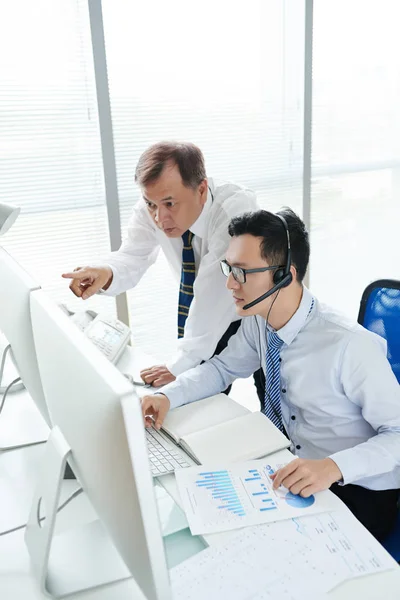 Stock brokers discussing data on computer monitors