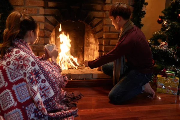 クリスマスの夜に燃えてそれを保つ人は暖炉に木を追加します — ストック写真