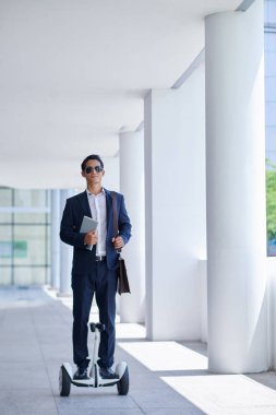 Genç girişimci gyro-scooter üzerinde bina ofis taşıma