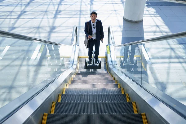Επιχειρηματία Στον Γυρο Σκούτερ Στέκεται Στο Τέλος Της Κυλιόμενης Σκάλας — Φωτογραφία Αρχείου