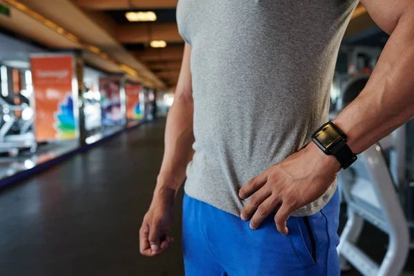 Cropped image of sportsman with smart watch on his wrist standing in gym