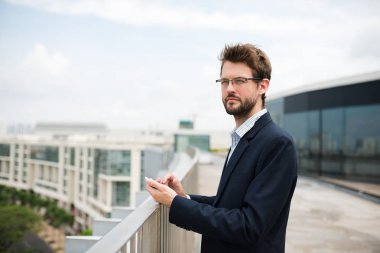 Genç işadamı ile smartphone ayakta binanın üstüne