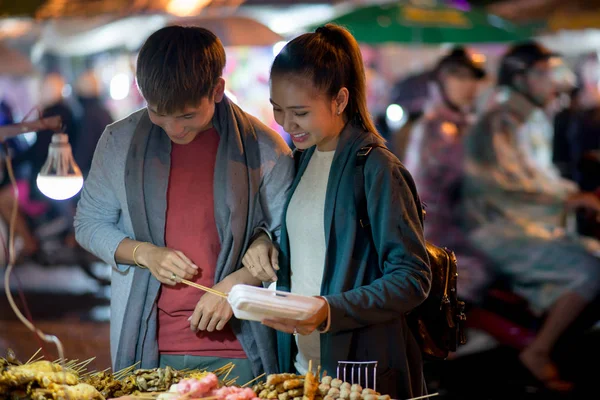 夕方には屋台の食べ物を買って陽気な若いアジアのカップル — ストック写真