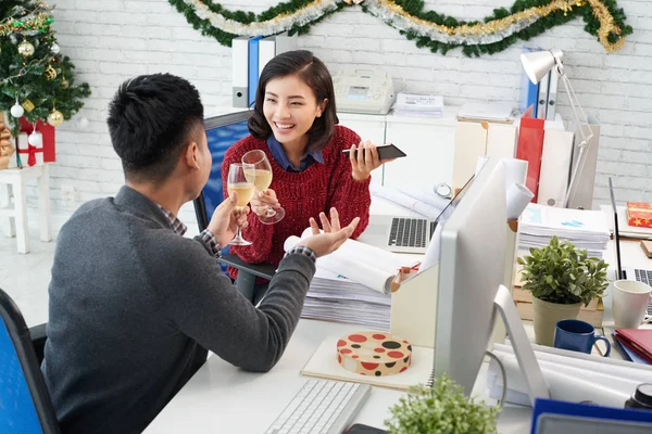 Cheerful Asian colleagues toasting with champagne at office in Christmas time