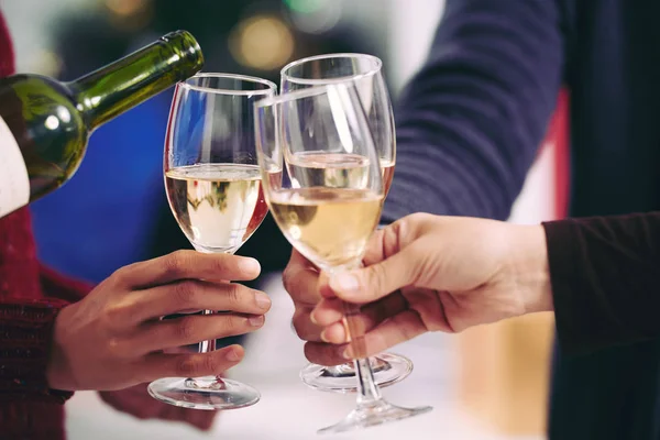 Close-up of three unrecognizable people toasting with wine glasses