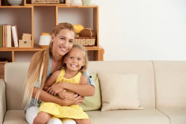 Küçük kızını sarılma ve kameraya bakarak mutlu anne portresi