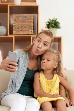 Genç anne ve kızı komik alarak yüz selfie birlikte evde ördek