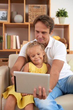 Baba ve kızı evde tablet bilgisayarda çizgi film izlerken