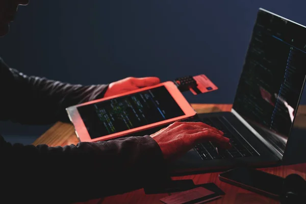 暗闇の中でデジタル タブレットを使用しているラップトップ上で個人データのハッキング男性の手のクローズ アップ — ストック写真