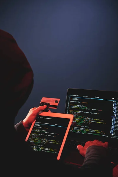 Rückseite der Hackerdatenbank für vermummte Internet-Kriminelle auf dem Laptop im Dunkeln — Stockbild Rückseite Der Hackerdatenbank Für Vermummte Internet Kriminelle Auf Dem Laptop — Stockfoto
