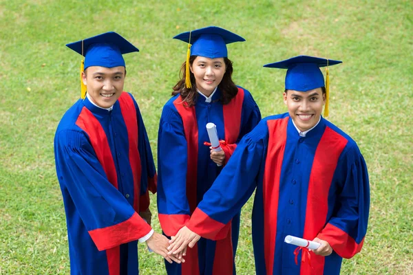 Asiáticos Graduados Juntando Mãos Enquanto Estão Livre Olhando Para Câmera — Fotografia de Stock