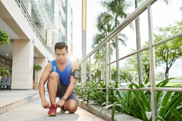 Confident Asian Sportsman Listening Music Smartphone While Tying His Shoelaces — Stock Photo, Image