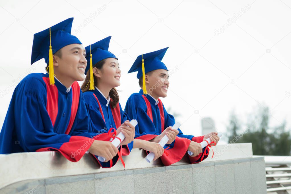 Profile view of enthusiastic graduates looking into distance