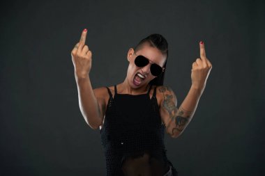Rebellious young woman in sunglasses showing middle fingers clipart