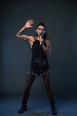 Kadın rocker bir şarkı söylerken tam uzunlukta portresi