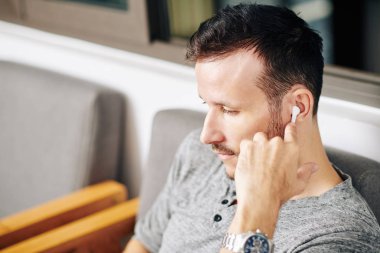 Kafede dizüstü bilgisayar bölümleri izlerken kulaklık takan ciddi sakallı bir adam.