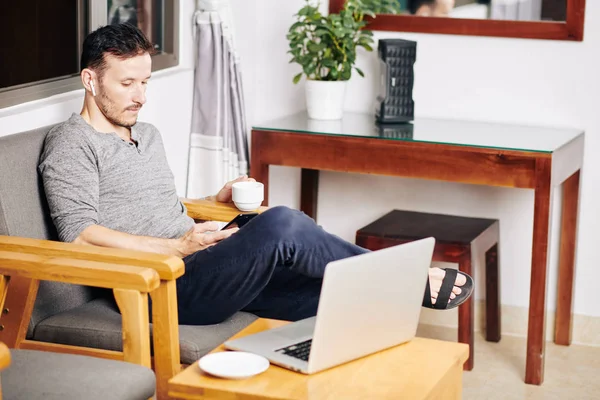 Junger Mann Genießt Tasse Kaffee Und Blättert Nach Der Arbeit — Stockfoto