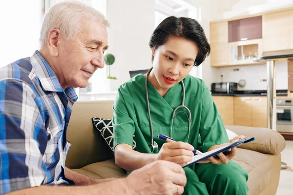 Young Vietnamese Nurse Vising Senior Patient Home Helping His Understanding — Stock Photo, Image