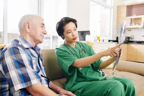 Senior Man Och Hans Sjuksköterska Sitter Soffan Hemma Och Diskuterar — Stockfoto