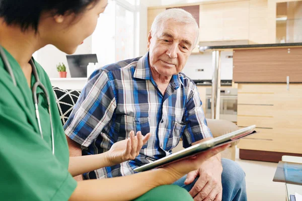 Pielęgniarka Odwiedza Staruszka Jego Mieszkaniu Wyjaśnia Jak Używać Tabletu Monitorowania — Zdjęcie stockowe