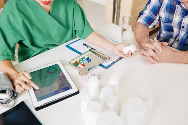 Female doctor checking food diary of senior patient via health application and prescribing him medicine