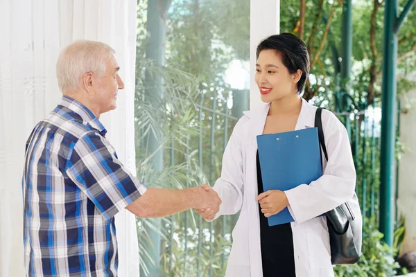 Leende Kvinnlig Läkare Med Urklipp Skakar Hand Senior Patient När — Stockfoto