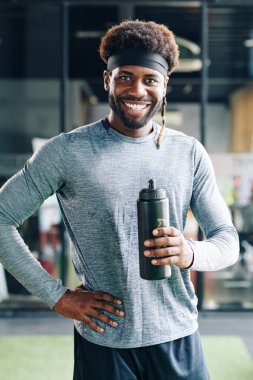 Yakışıklı fit zenci adamın portresi sabah spor salonunda çalışırken elinde bir şişe taze vitamin suyu tutuyordu.