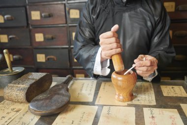 Eczacı, tıbbi tedavinin malzemelerini öğütmek için tokmak ve havan topu kullanıyor.