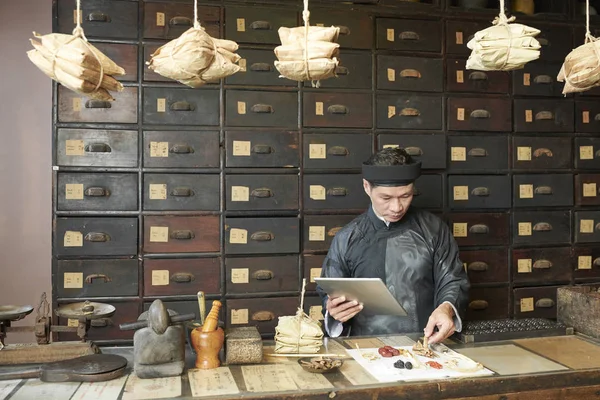 Serious Traditional Chinese Medicine Practitioner Tablet Computer Selecting Dry Herbs — ストック写真