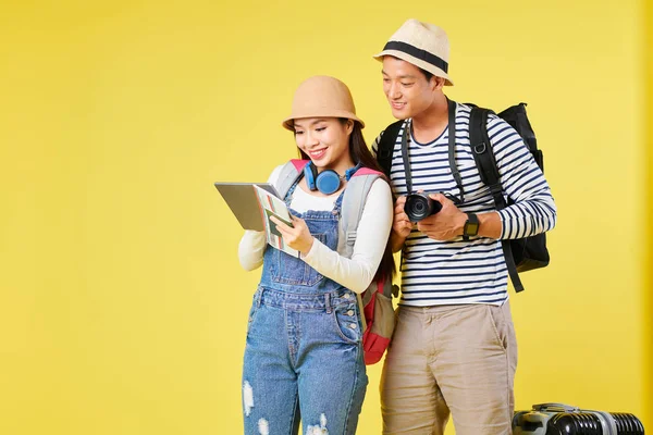 黄色に隔離されたホテルの部屋を予約するタブレットコンピュータ上のアプリケーションを使用して陽気な若いアジアの観光客 — ストック写真