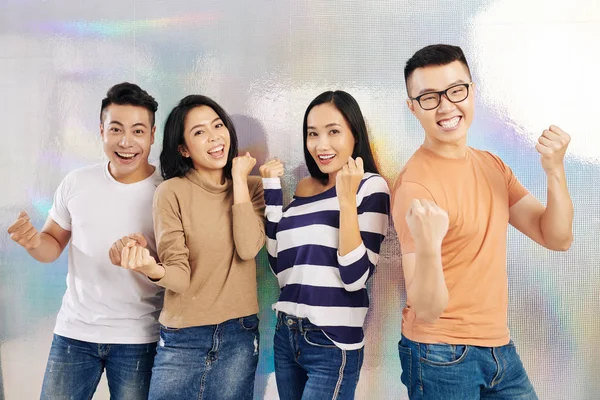 Group of excited happy young Asian people making fist bump when celebrating successful project