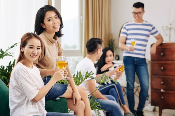 Pretty female friends having drinks when attending cozy party at home