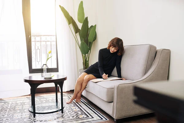 Preciosa Mujer Descalza Sonriente Sentada Sofá Escribiendo Planificador Sus Ideas — Foto de Stock