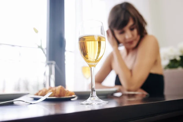 一个人坐在餐桌旁等待约会的年轻女子的一杯白葡萄酒 — 图库照片