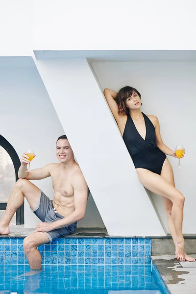 年轻的白种人夫妇在游泳池休息 喝着水果鸡尾酒 — 图库照片