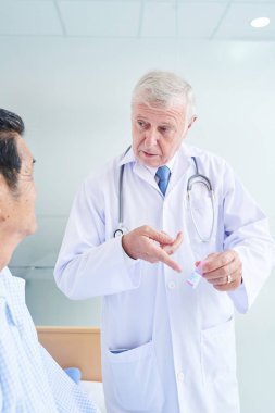 Deneyimli pratisyen hekim kıdemli hastaya bir şişe ilaç veriyor.