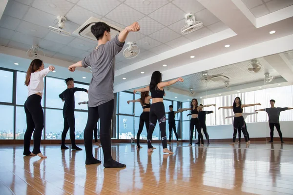 スタジオの大きな窓の前に立つダンサーのグループとフロント女性の後の動きを繰り返す — ストック写真