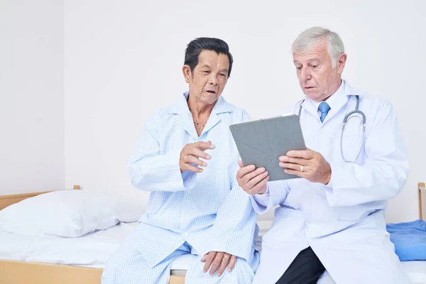 Médico Con Tablet Sentado Cama Del Paciente Mayor Discutiendo Con — Foto de Stock