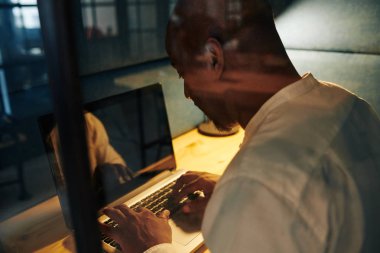 Siyahi işadamı projeyi son teslim tarihine kadar tamamlamak için bütün gece karanlık odada fazla mesai yapıyor.  