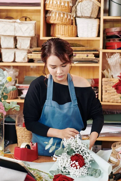 严肃的年轻女子在工作室工作 用彩色纸包着花束 — 图库照片