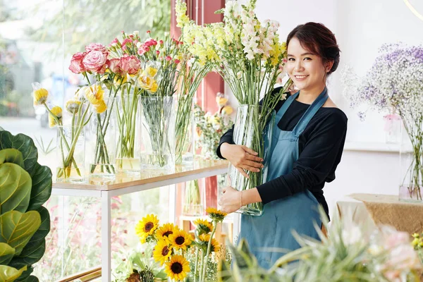 笑容可亲的年轻亚洲女人在花店里摆放着各种美丽花朵的花瓶 — 图库照片